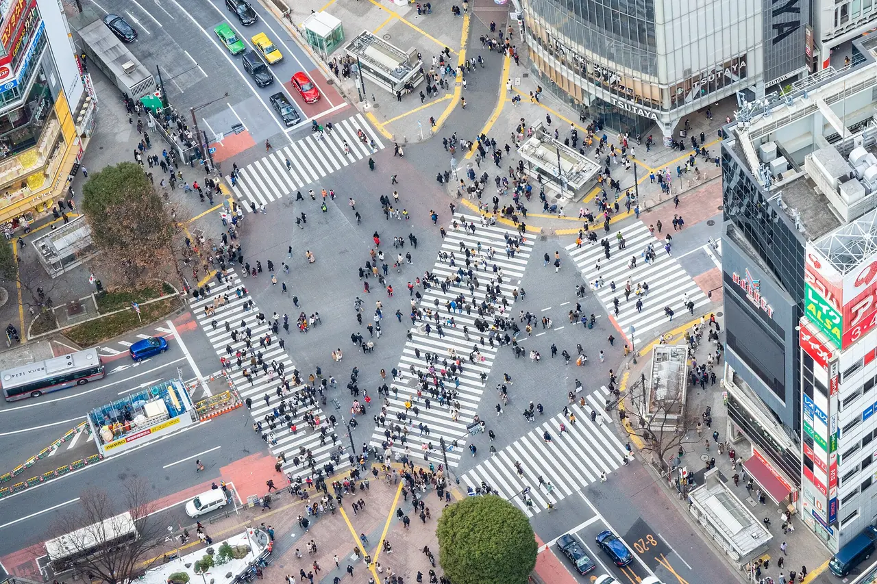 Shibuya Scramble Crossing widziane z góry, z tłumami przechodzącymi we wszystkich kierunkach