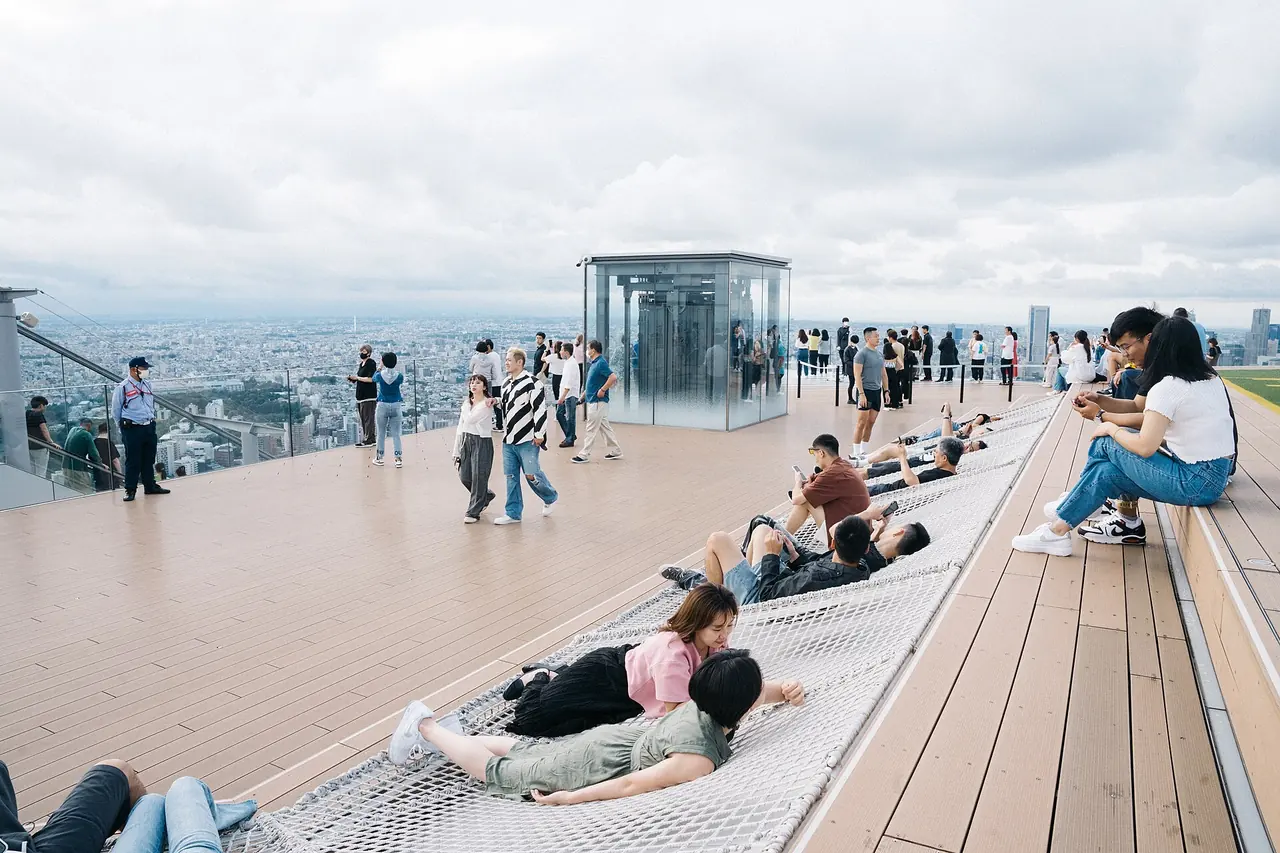 Goście leżący w sieciach Cloud Hammock na dachu SHIBUYA SKY