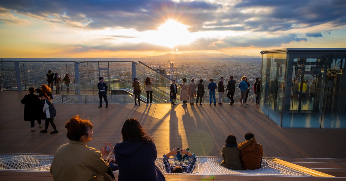 Besucher am Glasrand des Dachs von SHIBUYA SKY, mit Tokio darunter